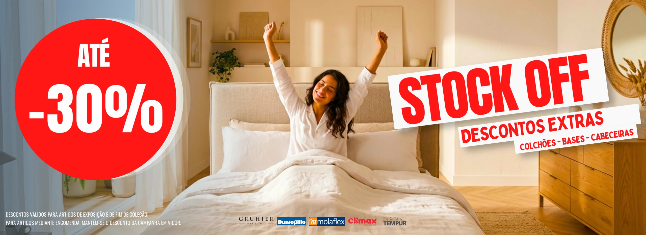 Banner promocional do Outlet dos Colchões com a mensagem 'Até -30% Stock Off: Descontos Extras em colchões, bases e cabeceiras'. Ao fundo, uma mulher a espreguiçar-se na cama.